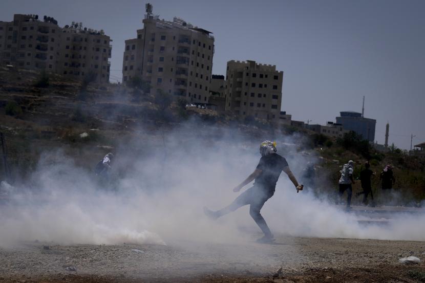 Pengunjuk rasa Palestina melarikan diri dari gas air mata selama bentrokan dengan pasukan Israel menyusul demonstrasi menentang serangan udara Israel di Jalur Gaza, dekat pemukiman Yahudi Tepi Barat Beit El, Sabtu, 6 Agustus 2022. Israel Ancam Targetkan Pemimpin Jihad Islam di Luar Negeri