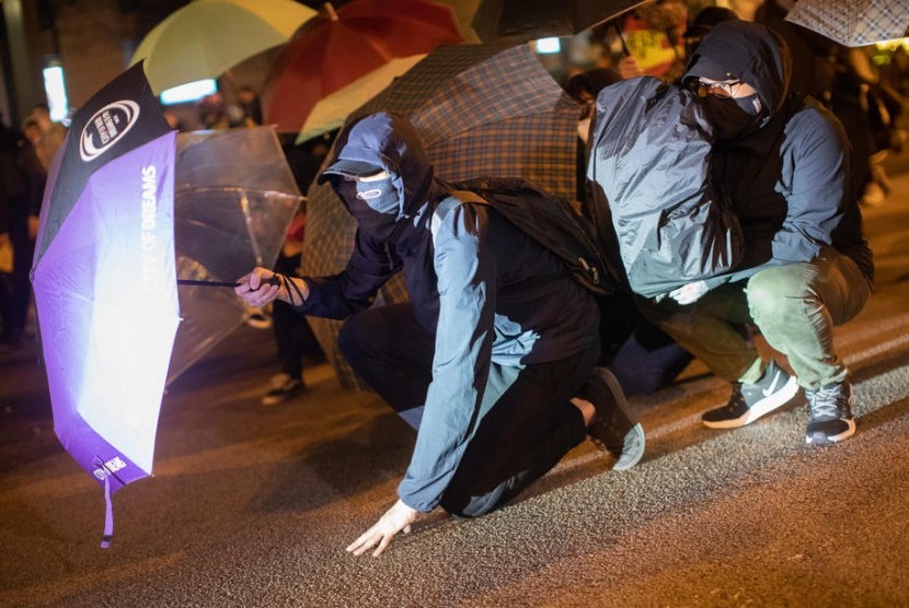 Pengunjuk rasa pro demokrasi berlindung menggunakan payung saat menghadapi polisi anti huru-hara di kawasan bisni Tsim Sha Tsui, Hong Kong, di Hong Kong, Selasa (24/12). Ratusan pengunjuk rasa antipemerintah di Hong Kong makan malam Natal bersama. Ilustrasi.
