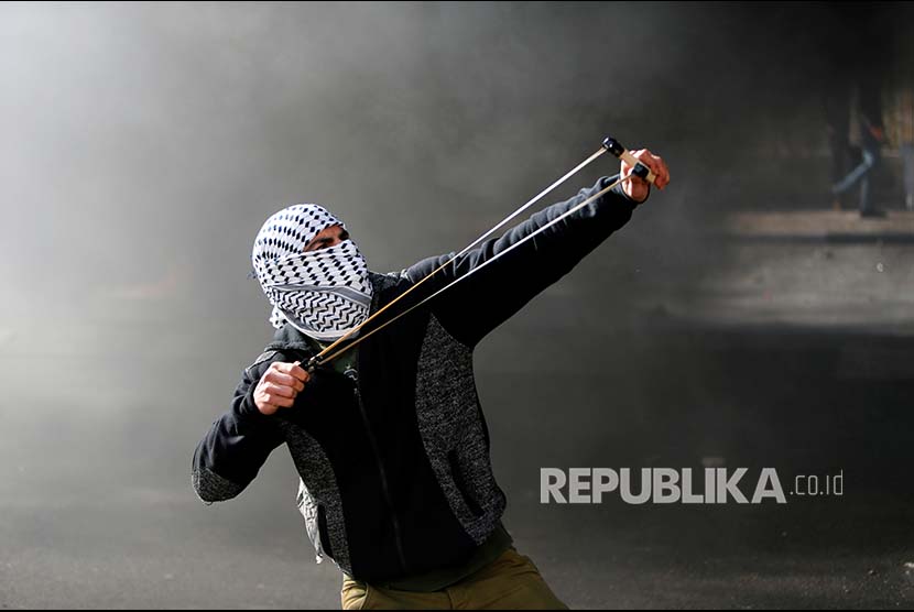 Pengunjukrasa melontarkan ketapel di sela unjuk rasa di Kota Bethlehem Tepi Barat, Palestina, Jumat (8/12)