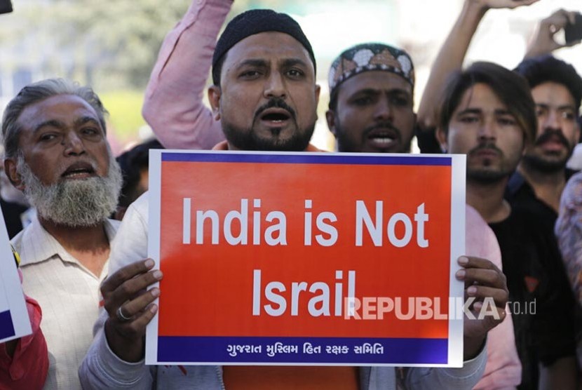 Pengunjukrasa penentang Revisi UU Kewarganegaraan India membawa poster menentang UU baru di Ahmadabad, India, Ahad (15/12)