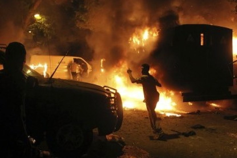 Pengunjukrasa terlihat di sela mobil-mobil yang terbakar akibat kerusuhan di Kedubes Israel di Kairo, Mesir, Sabtu.