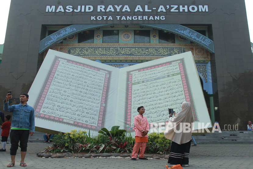 Pengunjung berfoto di depan replika Al Quran raksasa yang ada pada Festival Al Azhom 2019 di Tangerang, Banten, Senin (9/9/2019). Festival Al Azhom Kembali Digelar, Jadi Ajang Syiar Islam di Tangerang 