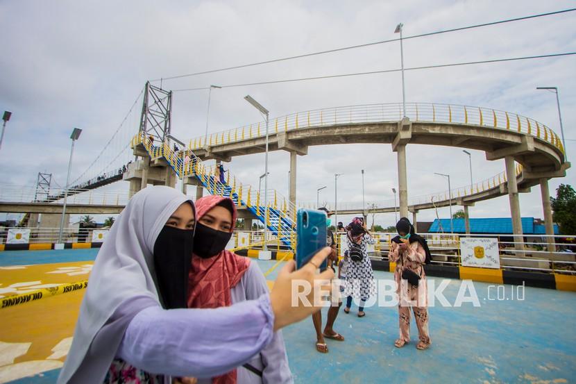 Pengunjung berfoto saat mengunjungi Jembatan Antasan Bromo di Banjarmasin, Kalimantan Selatan.