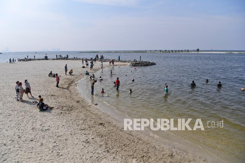 Pengunjung bermain di Pantai Ancol, Jakarta, Sabtu (7/11/2020). Pengelola Pantai Ancol menerapkan protokol kesehatan kepada pengunjung salah satunya memberikan imbauan agar tetap menjaga jarak dengan rombongan pengunjung lain untuk mencegah penularan COVID-19.
