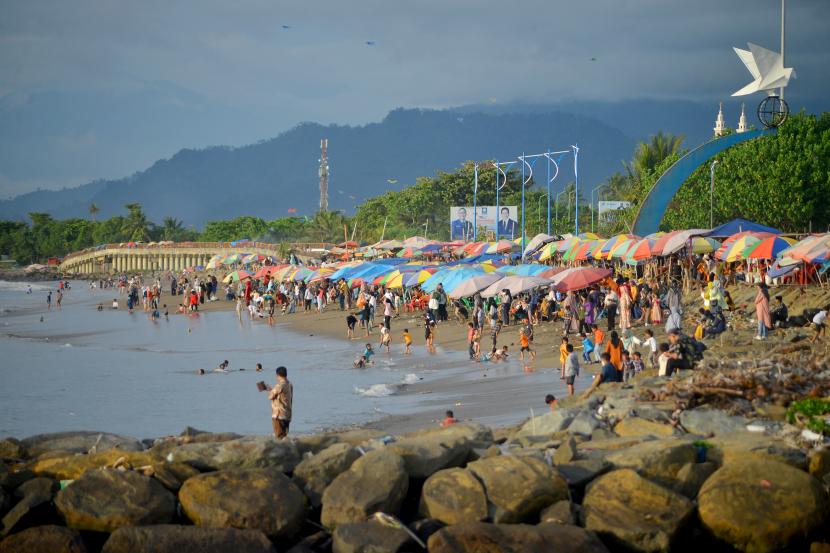 Pengunjung bermain di pantai Muaro Lasak, Padang, Sumatera Barat, Ahad (12/12/2021). Selama libur Natal dan Tahun Baru (Nataru), Pemkot Padang tetap membuka seluruh destinasi wisata di kota itu.