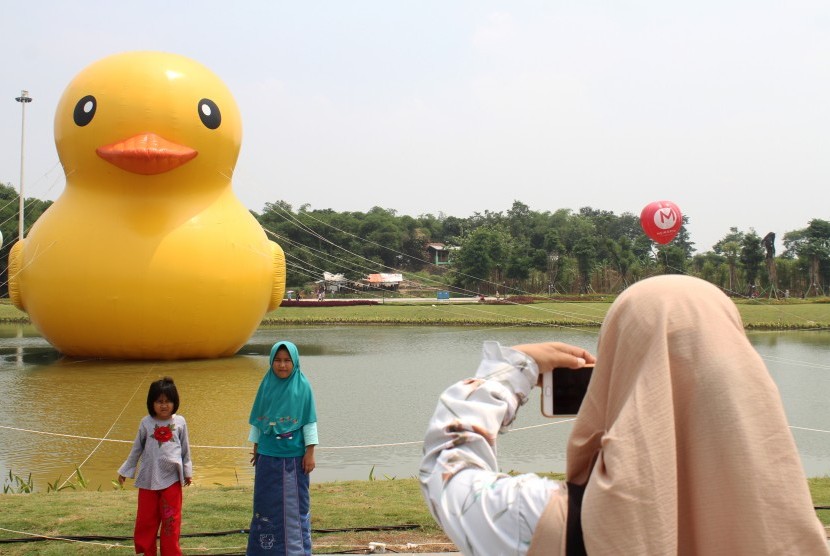 Pengunjung berpose foto dengan latar belakang patung bebek raksasa disela acara peluncuran Giant Yellow Duck, di Central Park Meikarta, Cikarang, Kabupaten Bekasi, Jawa Barat, Minggu (5/11). 