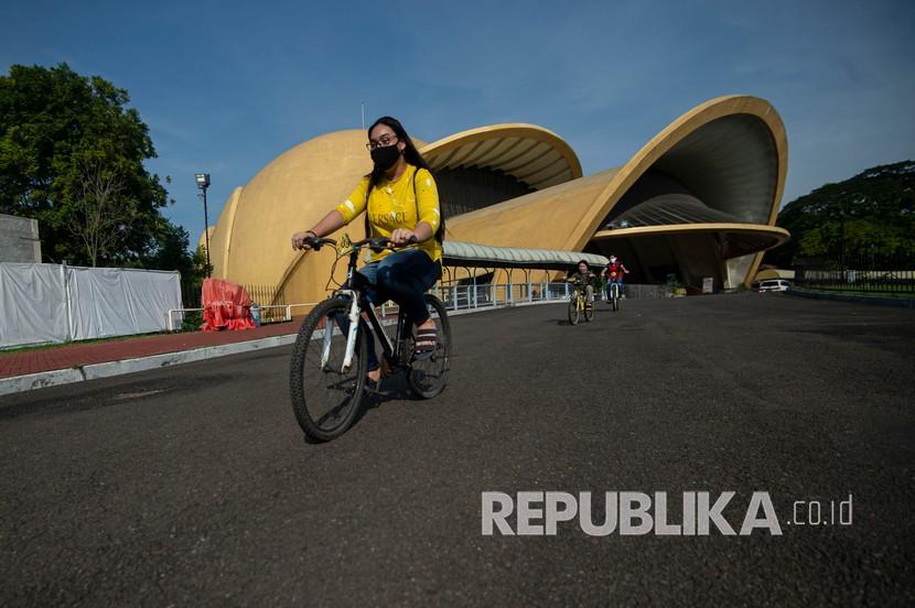 Pengunjung bersepeda melintas di depan Teater I-Max Keong Mas di Taman Mini Indonesia Indah (TMII), Jakarta, Selama PSBB, TMII akan ditutup bagi publik.