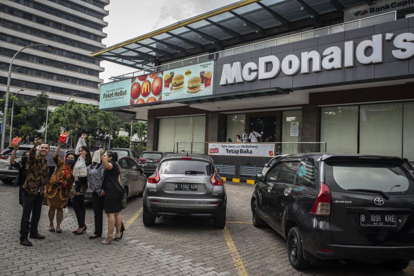 Pengunjung berswafoto seusai membeli makanan di gerai makanan cepat saji McDonald