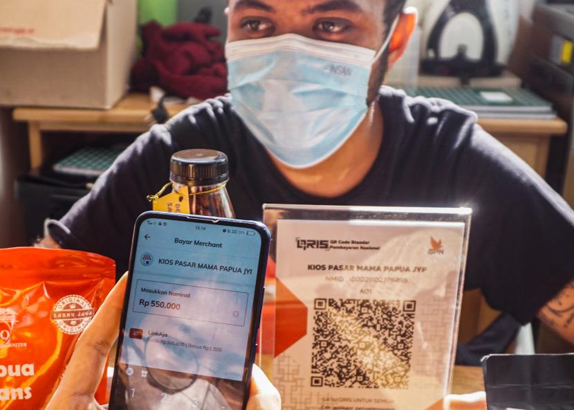 Pengunjung bertransaksi menggunakan QRIS di kios oleh-oleh pasar Mama-Mama Papua, Kota Jayapura, Provinsi Papua, Sabtu (23/10/2021). Kejahatan digital semakin marak dan menyasar pelaku UMKM sebagai korban.
