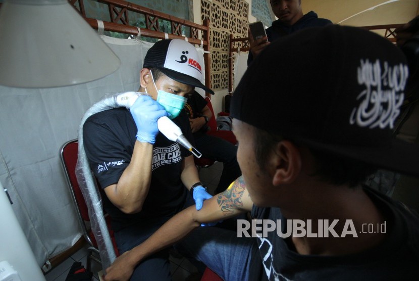 Pengunjung melakukan hapus tato di Hijrah Care pada acara Muhasabah Akhir Tahun Republika 2018, di Selasar Masjid Pusdai, Kota Bandung, Senin (31/12). 