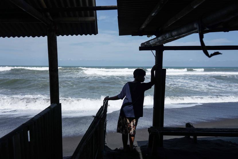 Pengunjung melihat bangunan yang terdampak abrasi akibat gelombang tinggi di Pantai Depok, Bantul, DI Yogyakarta, Ahad (17/7/2022). Badan Meteorologi, Klimatologi dan Geofisika (BMKG) mengeluarkan peringatan dini adanya gelombang tinggi yang mencapai enam meter di selatan pulau Jawa. 