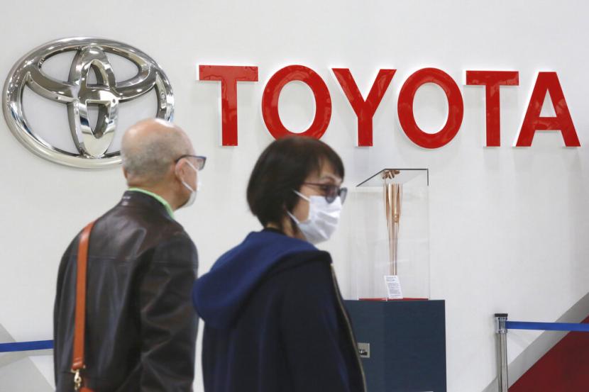 Pengunjung melintas di depan logo Toyota.