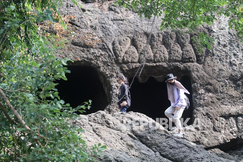 Pengunjung melintas di depan mulut Gua Selomangleng, Kota Kediri, Jawa Timur, Sabtu (12/6/2021). Gua Selomangleng yang terletak di kaki gunung Klotok tersebut menjadi obyek wisata andalan Kota Kediri. 