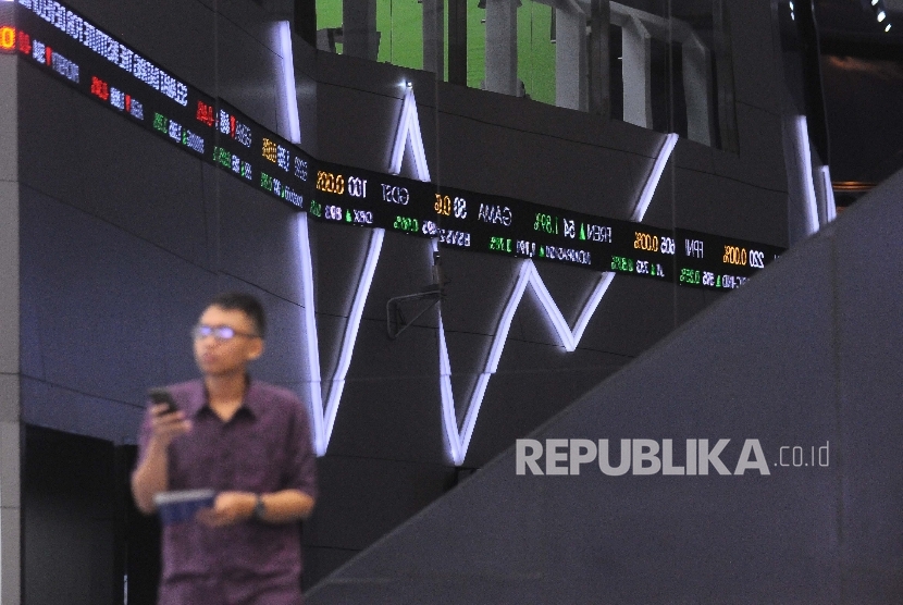 Pengunjung melintas didekat layar pergerakan Indeks Harga Saham Gabungan (IHSG) di Gedung Bursa Efek Indonesia (BEI), Jakarta, Selasa (4/4). 