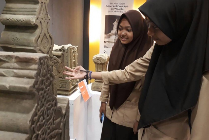 Pengunjung memerhatikan sebuah batu nisan di ajang  pameran batu nisan yang diadakan di Banda Aceh, 9-16 Mei 2017. 