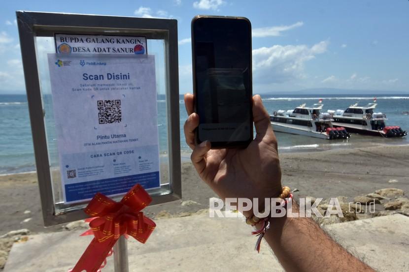 Pengunjung memindai kode batang sertifikat vaksin COVID-19 menggunakan aplikasi PeduliLindungi saat berkunjung di Pantai Sanur, Denpasar, Bali.