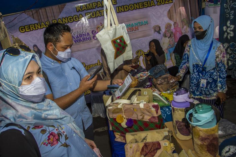 Pengunjung memindai kode QR saat bertransaksi di stand Rumah Kreatif dan Pintar pada Kampanye Gerakan Nasional Buatan Indonesia (Gernas BBI) di Taman Siring Nol Kilometer Banjarmasin, Kalimantan Selatan, Ahad (24/7/2022). Rumah Kreatif dan Pintar merupakan salah satu UMKM unggulan pada Kammpanye Gernas BBI dengan produk kain dan baju Sasirangan khas Kalimantan Selatan yang menggunakan pewarna alami agar ramah terhadap lingkungan. 