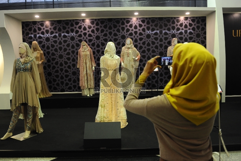 Pengunjung memotret koleksi busana saat menghadiri pameran Indonesia International Islamic Fashion & Product di JCC, Senayan, Jakarta, Rabu (9/9). 