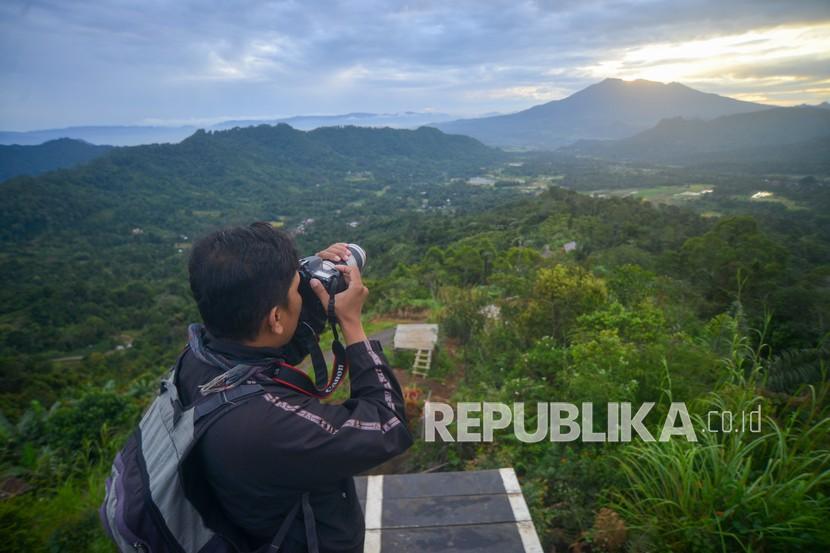 Pengunjung memotret panorama Gunung Sago, dari Puncak Data, Baso, Kabupaten Agam, Sumatera Barat, Sabtu (19/2/2022). Puncak Data dengan ketinggian 1.500 mdpl merupakan spot terbaik untuk menikmati panorama 360 derajat dengan pemandangan Gunung Marapi, Gunung Sago, dan Gunung Singgalang.