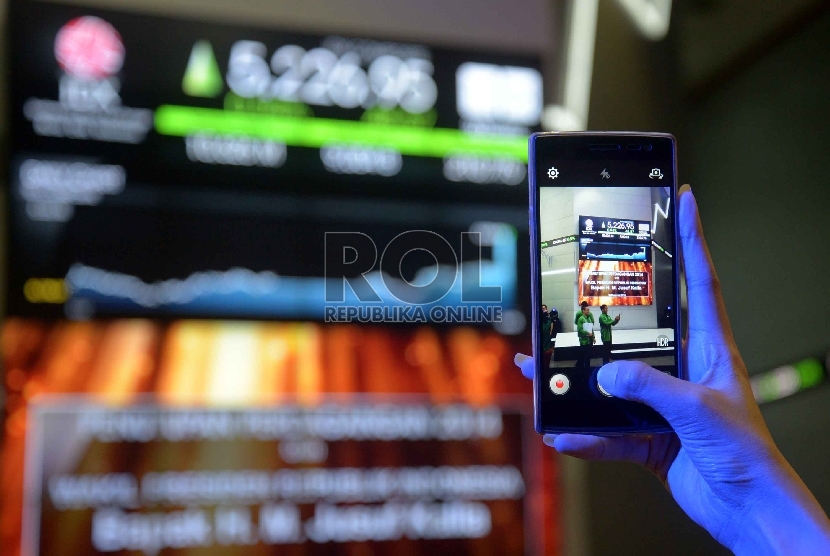  Pengunjung memotret tabel perdagangan saham saat penutupan perdagangan saham di Bursa Efek Indonesia (BEI).