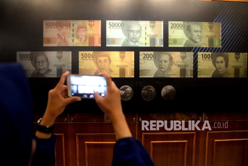 Pengunjung memotret uang Rupiah baru usai peresmian pengeluaran dan pengedaran uang Rupiah Tahu Emisi 2016 di Bank Indonesia, Jakarta, Senin (19/12).