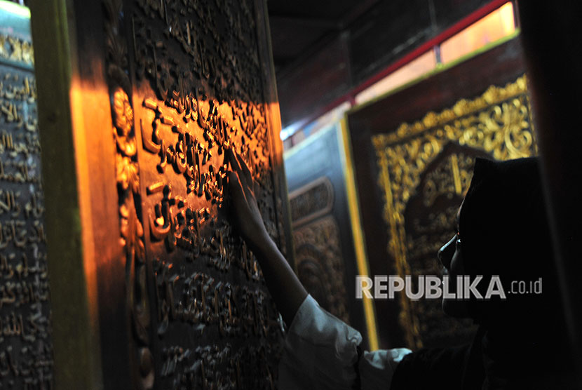 Pengunjung memperhatikan ukiran Alquran dari kayu trembesi di kawasan Bait Al Quran rakasasa Al Akbar Gandus Palembang, Sumatera Selatan, Senin (21/5). 