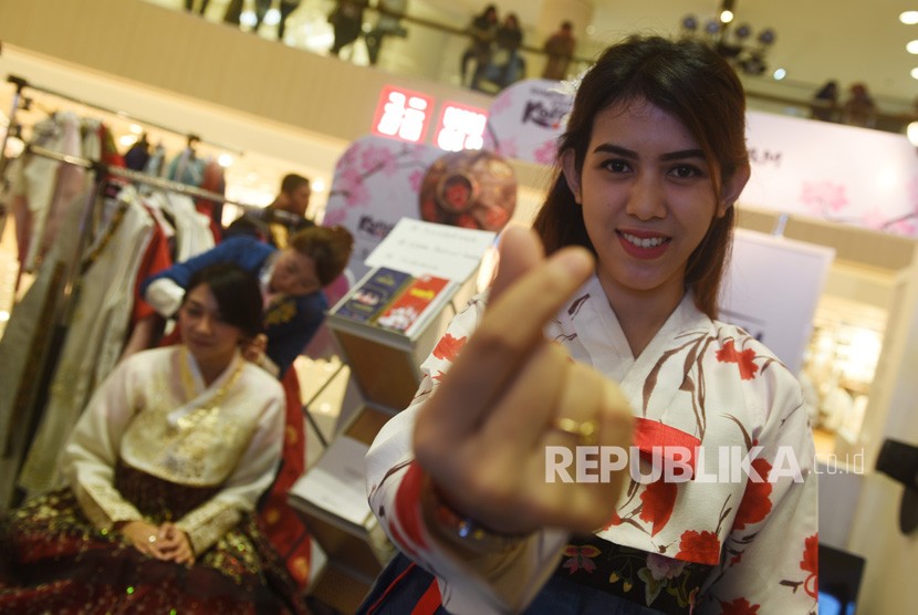Pengunjung mencoba mengenakan pakaian khas Korea saat Korea Festival di Surabaya, Jawa Timur, Jumat (2/3). 