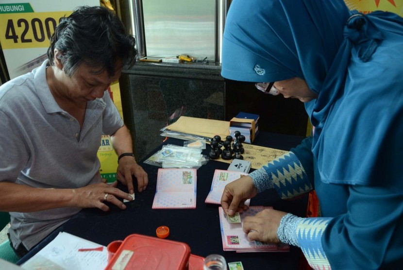 Pengunjung menempelkan perangko pada paspor filtelis pada 'Pameran Filateli Konferensi Asia Afrika (KAA) ke-60' di Gedung Wahana Bhakti Pos, Kota Bandung, Jumat (24/4). (Edi Yusuf/Republika)
