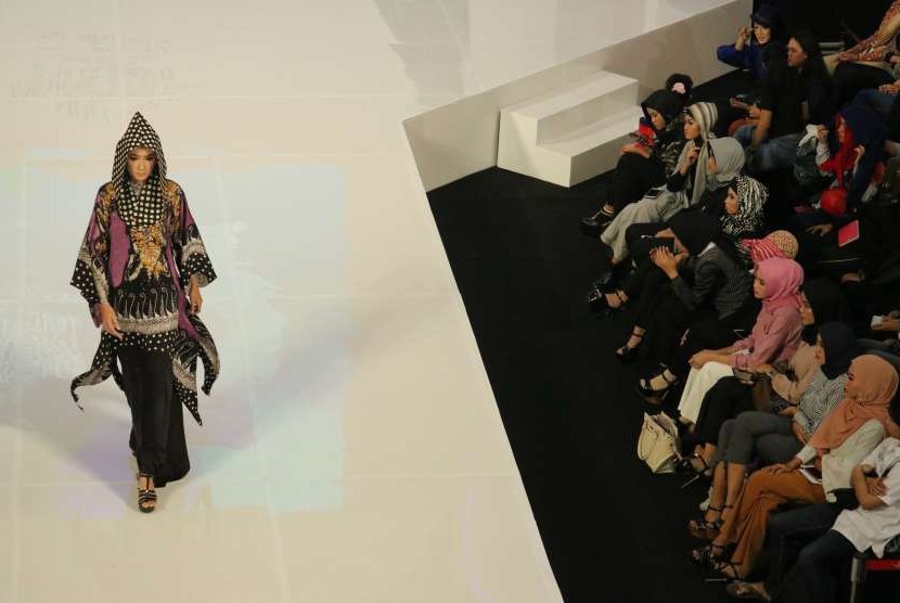 Pengunjung mengamati busana yang dikenakan seorang peragawati pada Moslem Fashion Festival di Surabaya, Jawa Timur, Jumat (12/10).