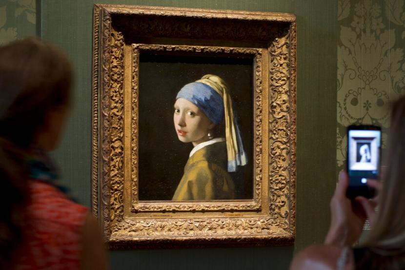 Pengunjung mengambil gambar lukisan Johannes Vermeers, Girl with a Pearl Earring (sekitar 1665) selama pratinjau untuk pers Mauritshuis yang direnovasi di Den Haag, Belanda, 20 Juni 2014. Mahakarya Vermeer telah menjadi karya seni terbaru yang ditargetkan oleh aktivis iklim dalam protes di museum Mauritshuis di Den Haag pada Kamis, 27 Oktober 2022.