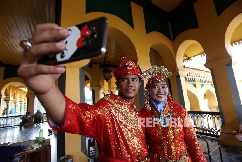 Pengunjung mengenakan pakaian adat melayu berfoto di dalam Istana Maimun, Medan, Sumatera Utara, Kamis (28/4).Republika/Rakhmawaty La'lang