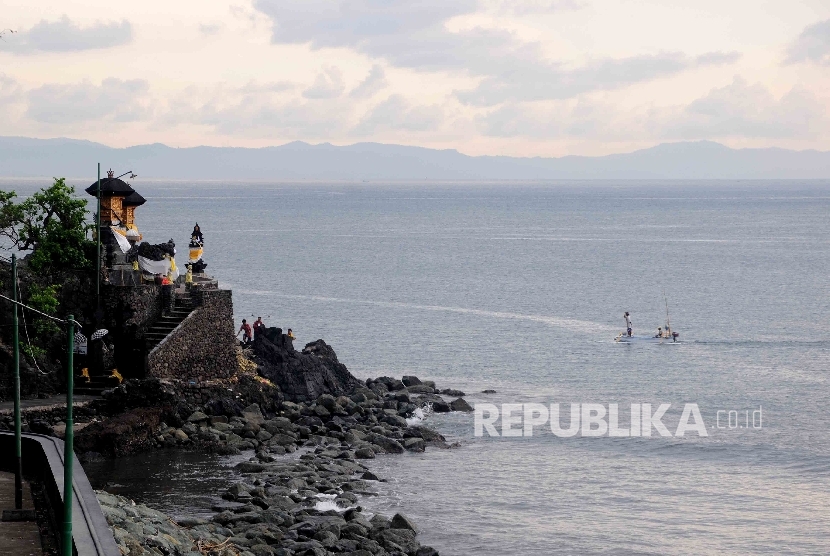 Pengunjung mengunakan sampan menikmati keindahan Pantai Sengigi, Lombok Barat, Nusa Tenggara Barat (NTB) Ahad (13/12).