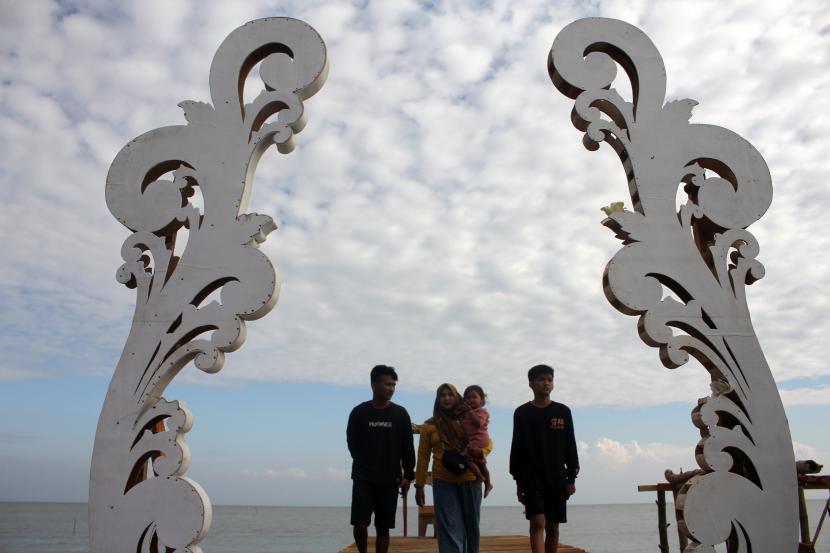 Pengunjung menikmati suasana sore hari di Wisata Watu Gendong, Bangkalan, Madura, Jawa Timur, Sabtu (16/7/2022). Destinasi wisata alam yang menawarkan pemandangan hutan mangrove dan lokasi berfoto tersebut ramai dikunjungi warga Pulau Madura saat akhir pekan. 