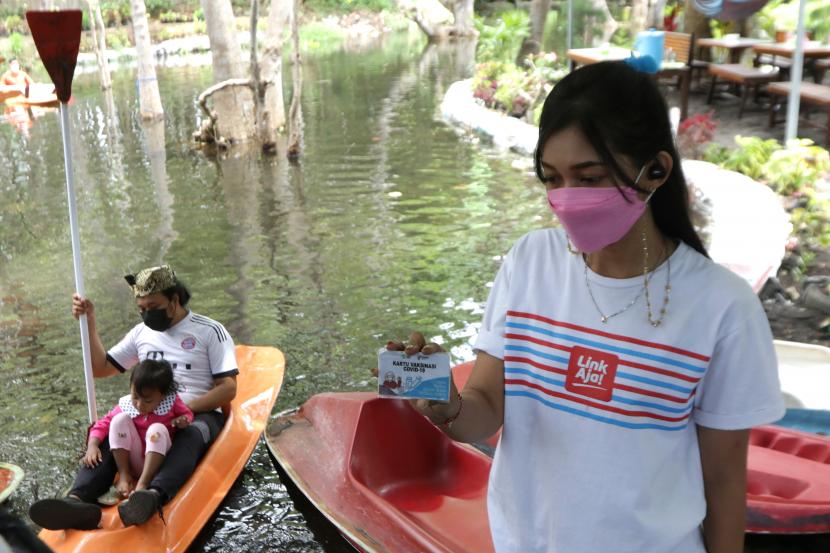 Pengunjung menunjukkan kartu vaksin untuk bermain kano setelah menerima vaksin COVID-19 di Pantai Cacalan, Banyuwangi, Jawa Timur, Sabtu (25/9/2021). Kegiatan vaksinasi di tempat wisata itu menyasar wisatawan yang belum melakukan vaksinasi dan diberikan bonus berupa satu tiket bermain kano.