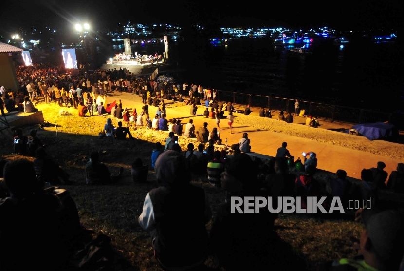 Pengunjung menyaksikan dari kejauhan panggung terapung di Pantai Bebas saat Konser Kemerdekaan Danau Toba.