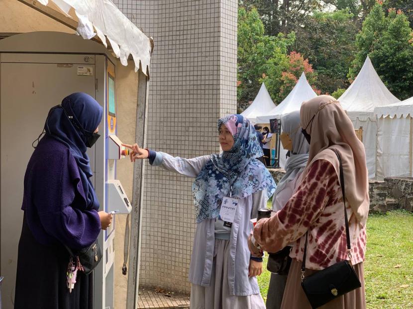 Pengunjung pameran sedang mencoba ATM beras.