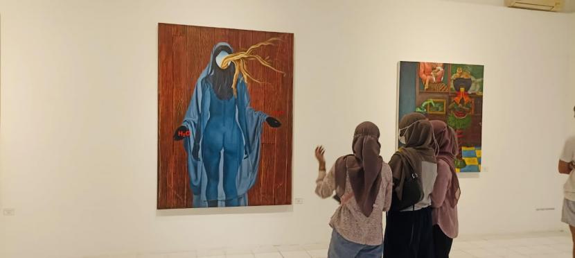 Pengunjung sedang melihat-lihat karya lukisan dari Kelompok Daun Gatal di Bentara Budaya, Kotabaru, Yogyakarta, (6/7/2022) malam.