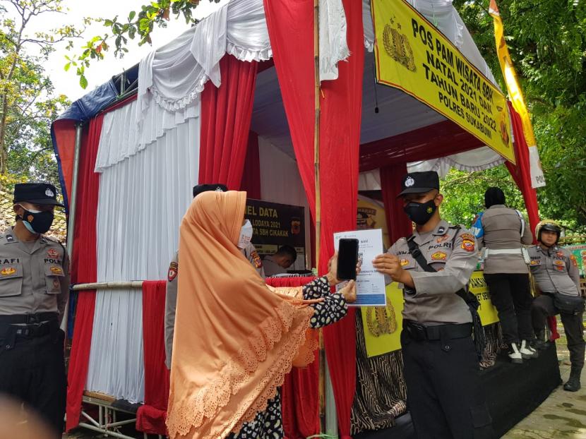 Pengunjung tengah melakukan scan barcode aplikasi pedulilindungi di Pantai SBH Palabuhanratu, Kabupaten Sukabumi, Ahad (26/12).