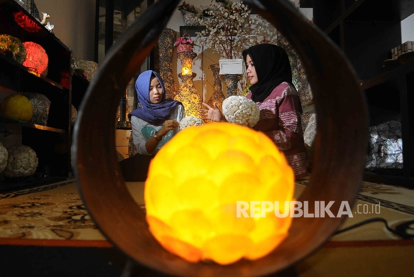  Pengusaha lampu hias berbahan kerang Cici Sri Sulastri (kanan) memantau pekerjanya saat memproduksi lampu hias di Citra Handicraft, Pamulang, Tanggerang Selatan, Banten, (21/12). 