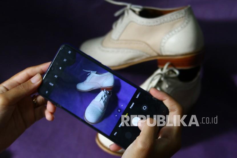 Pengusaha sepatu kulit memotret produknya untuk diunggah di pasar digital. 