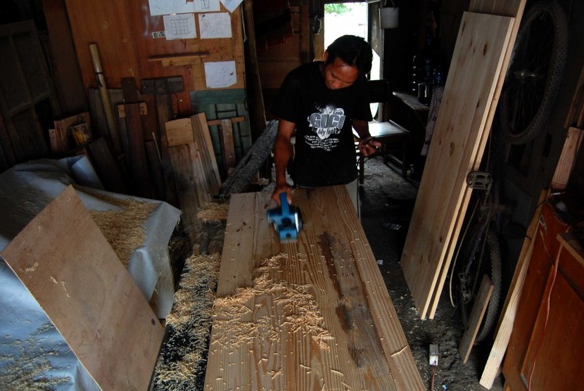 Pengusaha Usaha Kecil Menengah (UKM), Supri (30) menyerut papan pintu yang akan dijual di rumah produksi miliknya kawasan Lenteng Agung, Jakarta Selatan, Kamis (26/6). Dinas Koperasi Usaha Mikro Kecil dan Menengah (UMKM) meminta agar para pelaku UKM mening