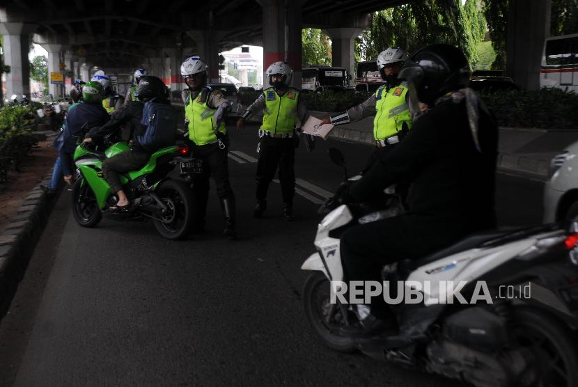 Polisi menghentikan pengendara motor yang melintas di jalur cepat saat melakukan Operasi Zebra di Jakarta Timur.