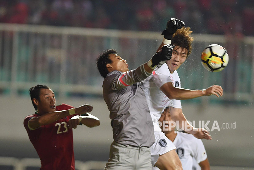 Penjaga Gawang Indonesia U-23 Muhammad Ridho (kiri) meninju bola mendahului tandukan pesepak bola korsel U-23 Hwang Yunsoo (kanan) dalam pertandingan ujicoba di Stadion Pakansari, Bogor, Sabtu (23/6). 