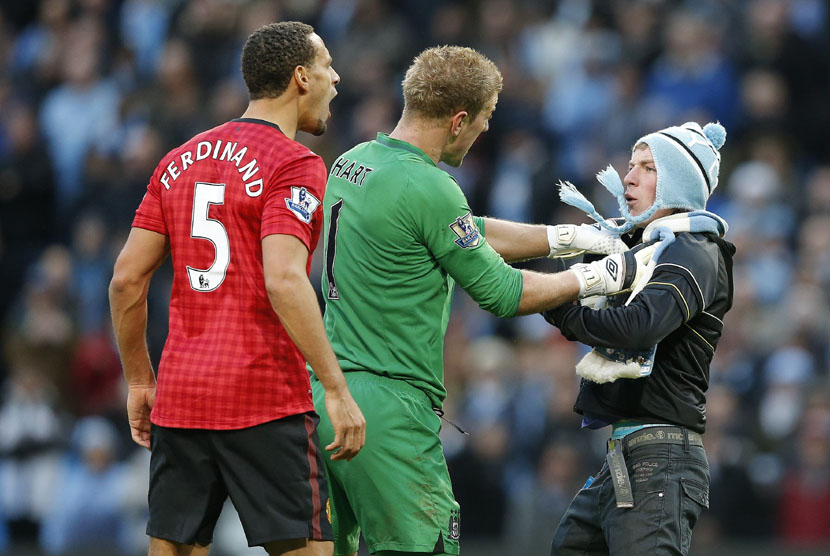  Penjaga gawang Manchester City Joe Hart mencegah pendukung Manchester City menghampiri pemain Manchester United Rio Ferdinand, setelah dihantam oleh sebuah benda yang dilemparkan dari arah penonton saat bertanding melawan Manchester City di Stadion Etihad