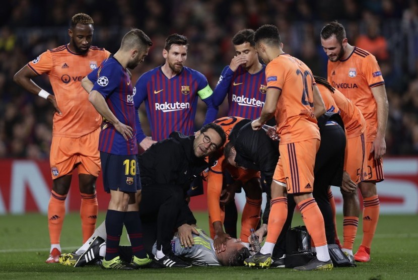 Penjaga gawang Olympique Lyon Anthony Lopes mendapatkan perawatan dari tim medis dalam laga melawan Barcelona.
