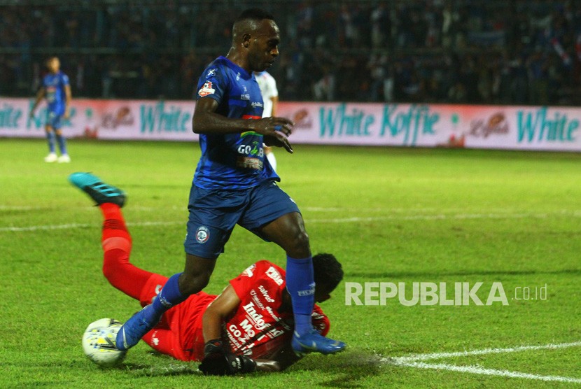 Penjaga gawang Persib Bandung Muhammad Agil Savik (bawah) berusaha menghalau bola dari kaki pesepakbola Arema FC Riki Kayame (kiri) dalam pertandingan Liga I di Stadion Kanjuruhan, Malang, Jawa Timur, Selasa (30/7/2019).