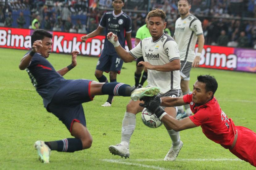 Penjaga gawang Persib Bandung, Reky Rahayu (kanan) menahan bola yang ditendang pesepak bola Arema FC, Dedik Setiawan (kiri) dalam laga lanjutan BRI Liga 1 di Stadion Kanjuruhan, Kabupaten Malang, Jawa Timur, Ahad (11/9/2022). Persib Bandung mengalahkan Arema FC dengan skor akhir 2-1. 