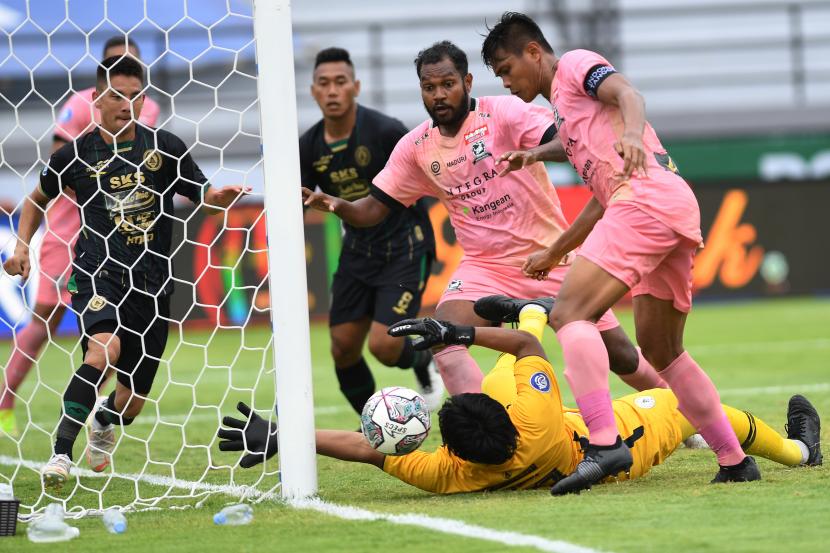 Penjaga gawang PSS Sleman Miswar Saputra (bawah) berusaha menyelamatkan gawangnya dari serangan pemain Madura United Fachruddin (kanan) dalam pertandingan sepak bola Liga 1 di Stadion I Wayan Dipta, Gianyar Bali, Selasa (18/1/2022). Pertandingan berakhir imbang dengan skor 1-1.