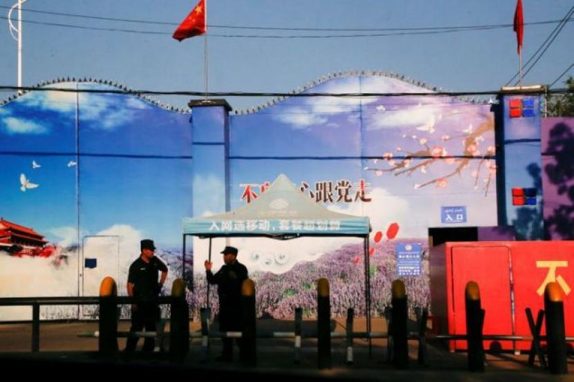 penjaga keamanan berdiri di gerbang yang secara resmi dikenal sebagai pusat pendidikan keterampilan kejuruan di Huocheng .