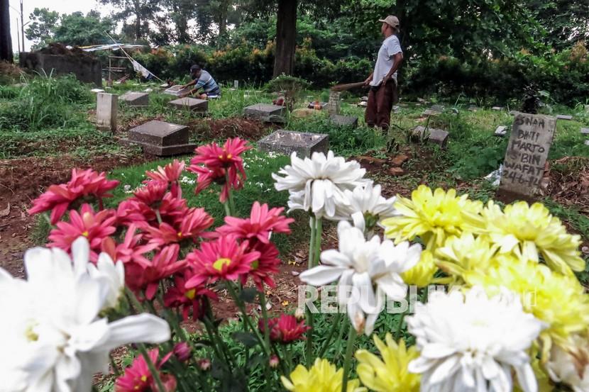 Penjaga makam membersihkan makam di Tempat Pemakaman Umum Pondok Rajeg, Kabupaten Bogor.